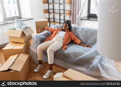 moving, people and real estate concept - tired woman with boxes sleeping on sofa at new home. tired woman sleeping on sofa moving to new home