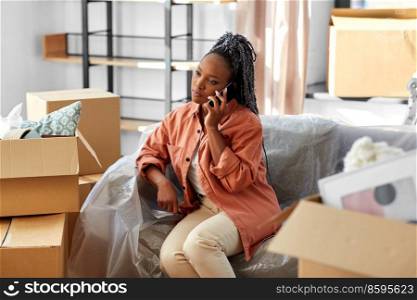 moving, people and real estate concept - woman with boxes calling on smartphone at new home. woman calling on phone moving to new home