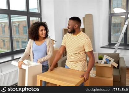 moving, people, repair and real estate concept - happy african american couple with tables stuff at new home. happy couple moving to new home