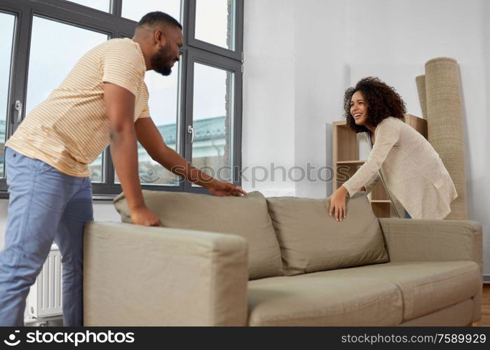 moving, people, repair and real estate concept - happy african american couple with sofa at new home. happy couple moving to new home