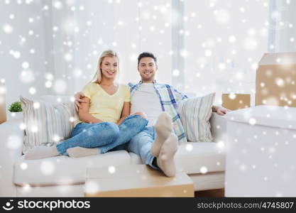 moving, people, repair and real estate concept - happy couple with big cardboard boxes on sofa at new home over snow