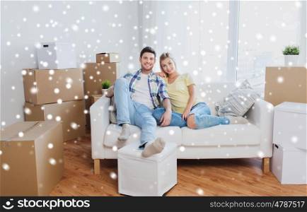 moving, people, repair and real estate concept - happy couple with big cardboard boxes on sofa at new home over snow