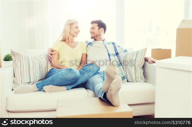 moving, people, repair and real estate concept - happy couple with big cardboard boxes on sofa at new home. happy couple with big cardboard boxes at new home