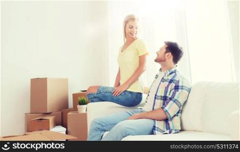 moving, people, repair and real estate concept - happy couple with big cardboard boxes on sofa at new home. happy couple with big cardboard boxes at new home