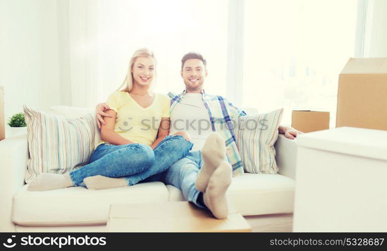 moving, people, repair and real estate concept - happy couple with big cardboard boxes on sofa at new home. happy couple with big cardboard boxes at new home