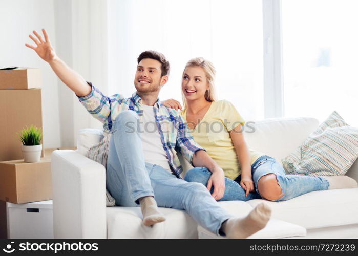 moving, people, repair and real estate concept - happy couple with big cardboard boxes on sofa at new home. happy couple with cardboard boxes at new home