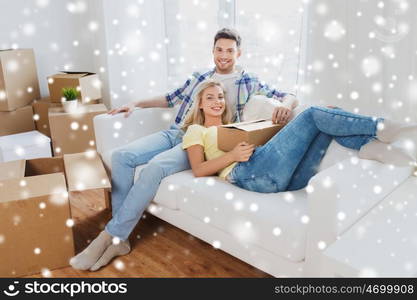 moving, people, repair and real estate concept - happy couple with cardboard boxes on sofa at new home over snow