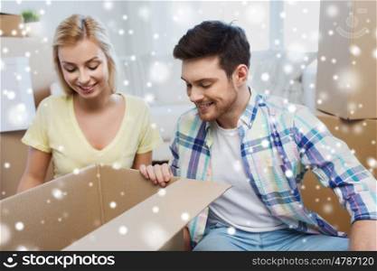 moving, people, repair and real estate concept - smiling couple looking into big cardboard box at new home over snow