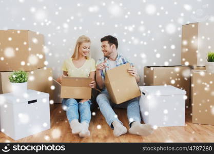 moving, people, repair and real estate concept - smiling couple looking into big cardboard box at new home over snow