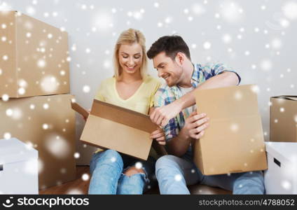 moving, people, repair and real estate concept - smiling couple looking into big cardboard box at new home over snow