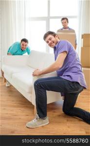 moving, real estate and friendship concept - smiling male friends with sofa and boxes at new home