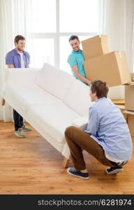 moving, real estate and friendship concept - smiling male friends with sofa and boxes at new home