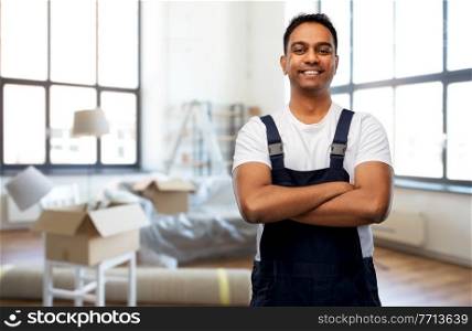 moving, repair and people concept - happy smiling indian worker, loader or repairman with crossed arms over new home background. happy indian worker with crossed arms at new home