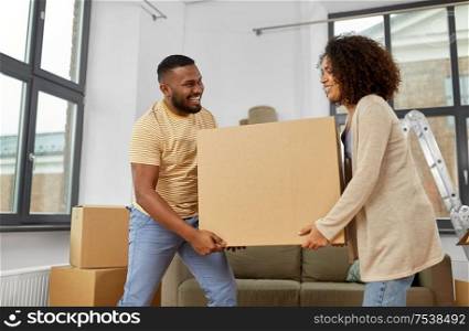 moving, repair and real estate concept - happy african american couple carrying big cardboard box together at new home. happy couple with boxes moving to new home