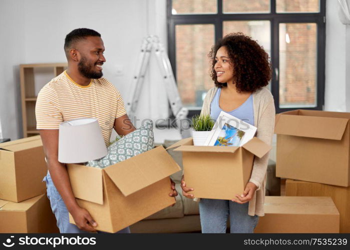 moving, repair and real estate concept - happy african american couple with stuff in cardboard boxes at new home. happy couple with boxes moving to new home
