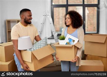 moving, repair and real estate concept - happy african american couple with stuff in cardboard boxes at new home. happy couple with boxes moving to new home