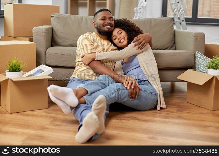 moving, repair and real estate concept - happy african american couple with cardboard boxes hugging at new home. happy couple with boxes moving to new home