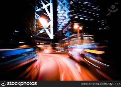 Moving through modern city street with illuminated skyscrapers. Hong Kong.&#xA;Abstract cityscape traffic background with motion blur, art toning