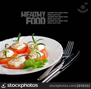 Mozzarella and tomato with rosemary on white plate in black background.