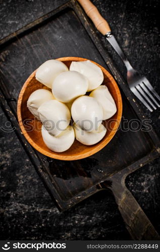 Mozzarella cheese on a cutting board with salt. On a black background. High quality photo. Mozzarella cheese on a cutting board with salt.