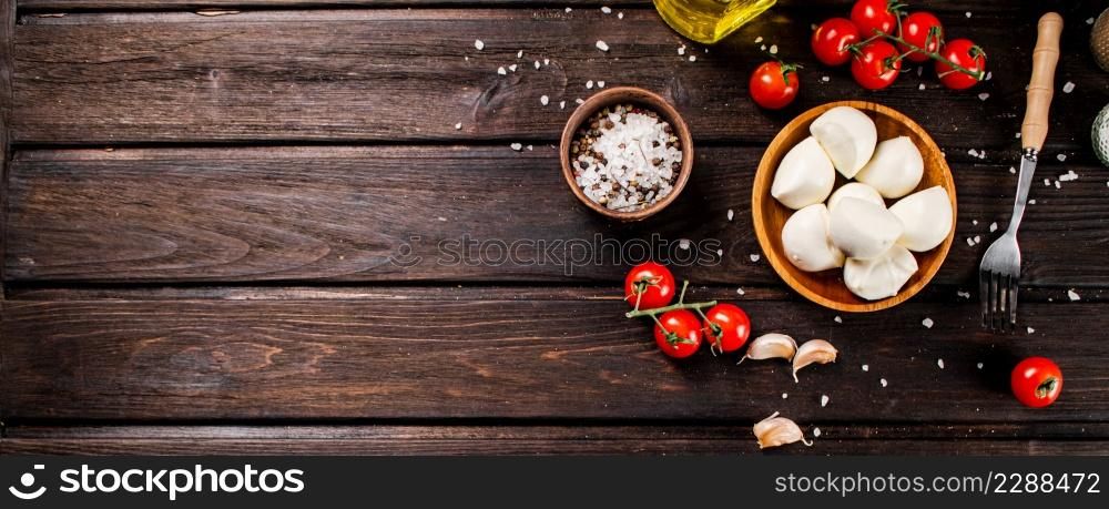 Mozzarella cheese on a plate on a table with tomatoes and spices. On a wooden background. High quality photo. Mozzarella cheese on a plate on a table with tomatoes and spices.