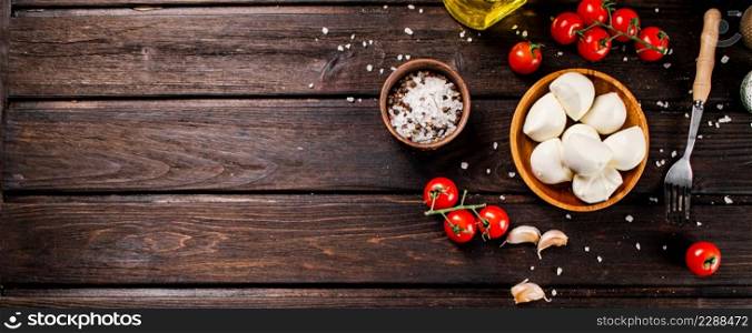 Mozzarella cheese on a plate on a table with tomatoes and spices. On a wooden background. High quality photo. Mozzarella cheese on a plate on a table with tomatoes and spices.