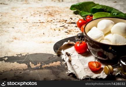 Mozzarella cheese, tomatoes, olive oil and an old knife. On rustic background. Mozzarella cheese, tomatoes, olive oil and an old knife.