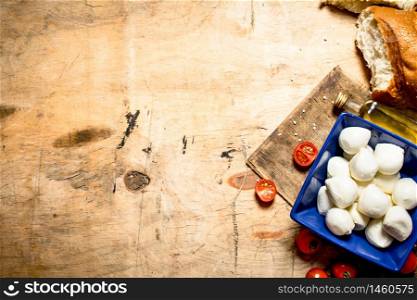 Mozzarella with fresh bread and tomatoes. On a wooden table.. Mozzarella with fresh bread and tomatoes.