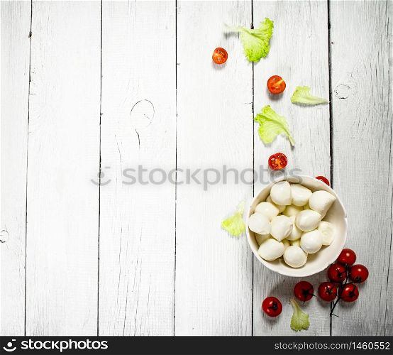Mozzarella with tomatoes and herbs .On a white wooden background.. Mozzarella with tomatoes and herbs
