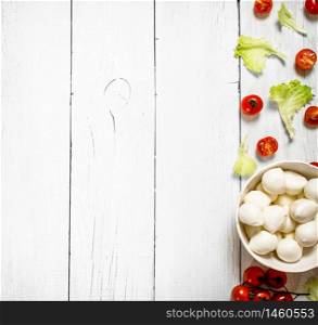 Mozzarella with tomatoes and herbs .On a white wooden background.. Mozzarella with tomatoes and herbs