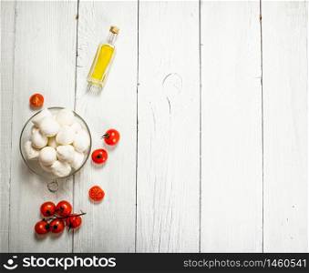Mozzarella with tomatoes and olive oil. On a white wooden background.. Mozzarella with tomatoes and olive oil.