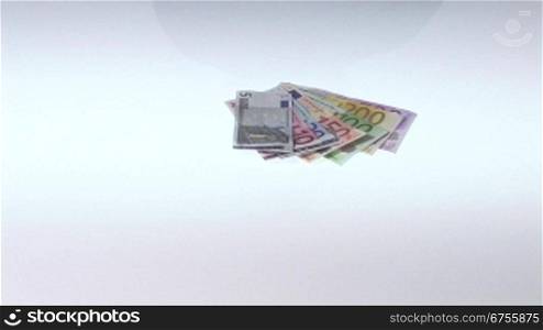MSnnerhand wirft einen FScher Geldscheine auf eine Tischplatte.