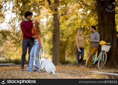 Mu<iracial young coup≤walking with dog in autumn park