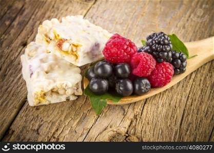 muesli bars with fresh berries on wooden background