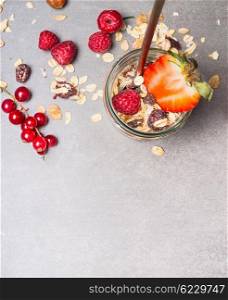 Muesli with oat flakes, dried fruits, nuts and fresh berries. Muesli in glass jar, top view. Healthy food and Clean Eating concept