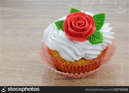 Muffin with butter cream decorated red sugar rose