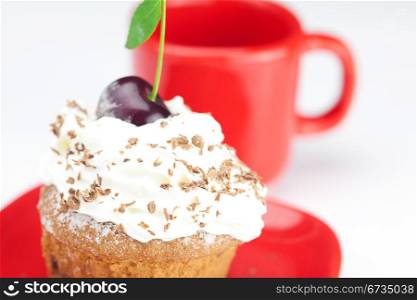 muffin with whipped cream, cherries and red cup on white background