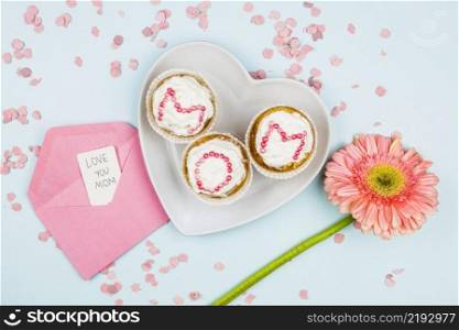 muffins with mom word plate near flower envelope with tag confetti