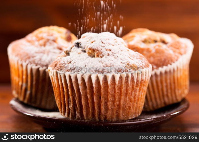 muffins with powdered sugar on wooden table