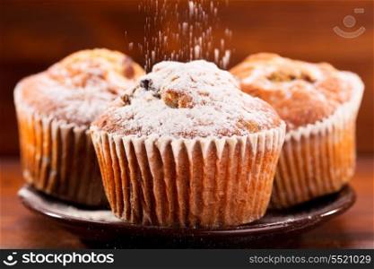 muffins with powdered sugar on wooden table