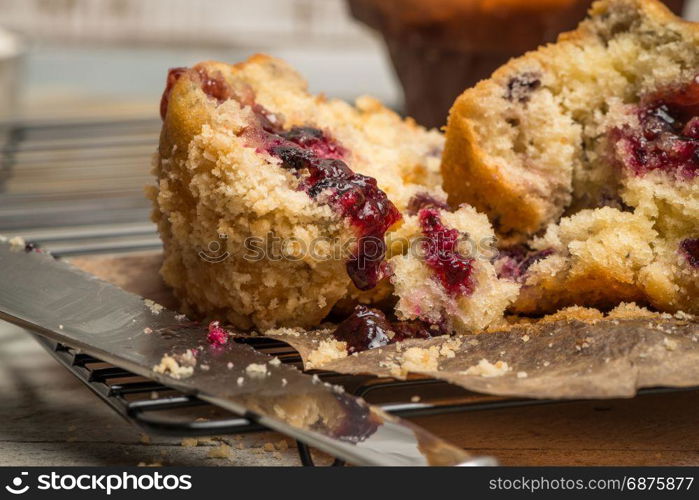 Muffins with red fruits jam fill on wooden counter top.