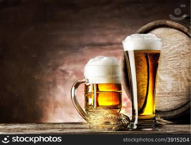 Mug and a glass of light beer on background of old barrels. Mug and a glass of light beer