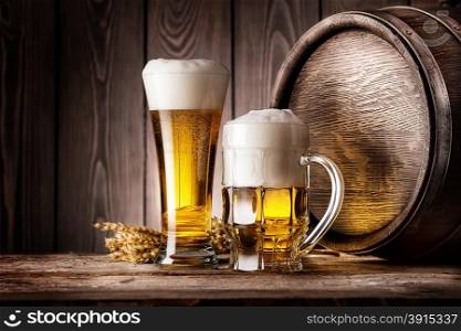 Mug and a glass of light beer with ears of barley and wooden barrel. Mug and a glass of light beer with ears of barley