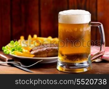 mug of beer with plate of grilled sausages