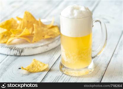 Mug of beer with tortilla chips on the wooden table