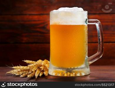 mug of beer with wheat on wooden table
