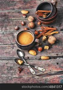 mug of coffee,almonds,cinnamon and nuts on rustic background