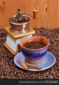 mug of coffee and roasted coffee beans with retro copper manual mill, cinnamon