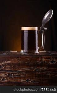 Mug of dark beer standing on a wooden chest