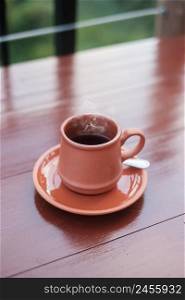 mug of hot coffee or tea on wooden table in the morning with mountain and nature background
